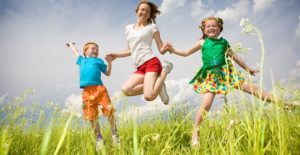 children happily jump through a field during summer