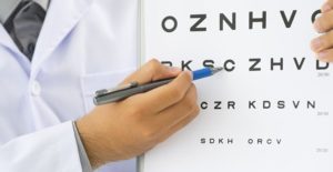 an eye doctor points at an eye letter chart