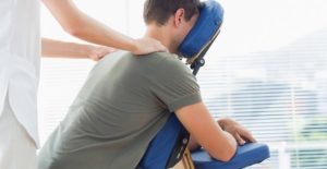 a massage therapist works on the shoulders of a client