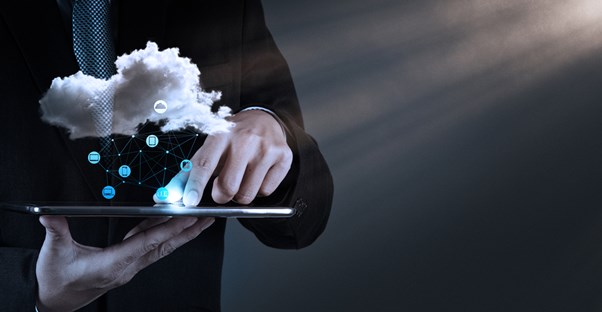 a concept image of a man using a tablet and a symbolic cloud hovers over it