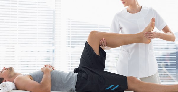 a massage therapist moves the leg of a client