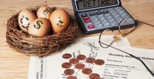 a desk with calculator, pennies, and a nest with eggs on them symbolizing retirement funds