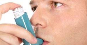 a young man uses his blue inhaler as an asthma treatment