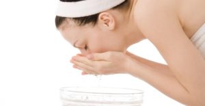 a woman washers her face to treat a blackhead