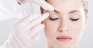 a doctor examines a woman's eyebrows to prep for cosmetic surgery