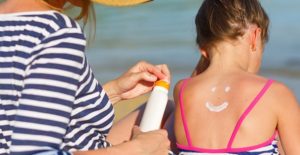 a mom applies sunburn lotion to her daughter's back